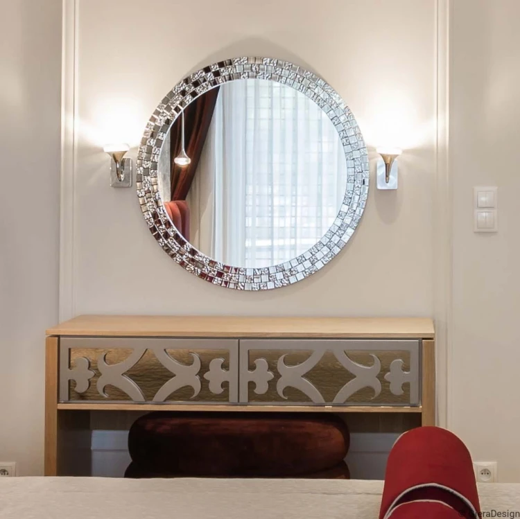 Eleganckie lustro Aurea w ramie ze srebrnej mozaiki glamour wiszące pomiędzy  kinkietami na ścianie nad komodą w sypialni. GieraDesign
