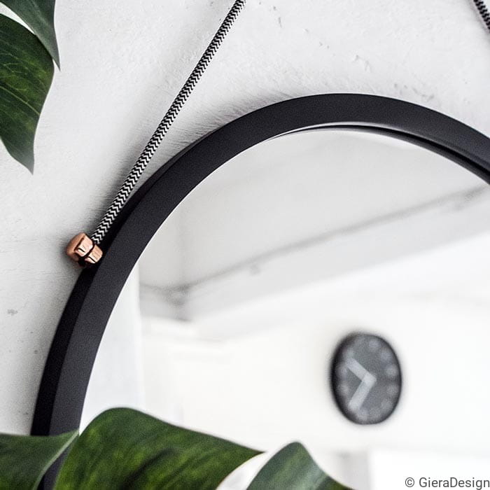 Zbliżenie na lustro wiszące Scandi Power Chevron w czarnej ramie. GieraDesign