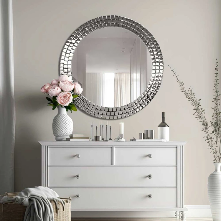 Okragłe lustro Aurora Silver ze srebrną mozaiką w stylu glamour nad białą komodą w salonie. GieraDesign