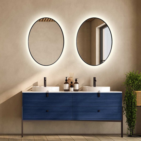 Podświetlane lustro Scandi slim owalne w wąskiej czarnej ramie, nad granatową szafką z szufladami.