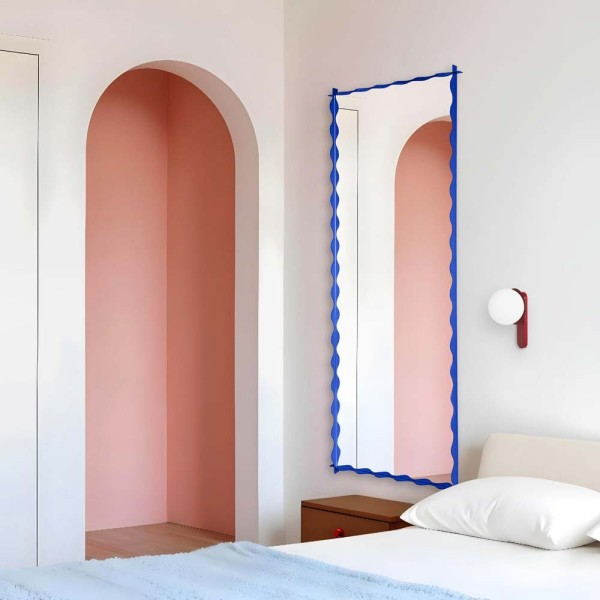 Lustro Monda Wave w niebieskiej pofalowanej ramie zawieszone w sypialni. Lustro GieraDesign