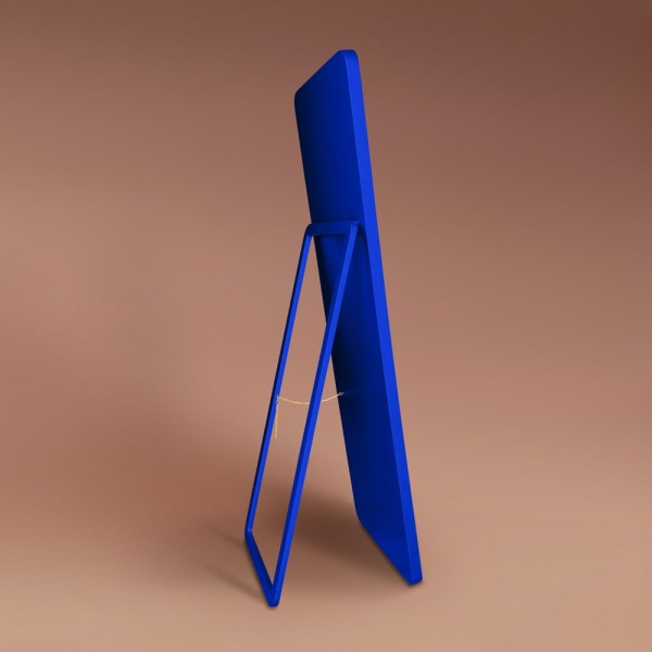 Lustro stojące Billet w niebieskiej ramie, oparte na nodze zintegrowanej z plecami lustra.  Producent GieraDesign