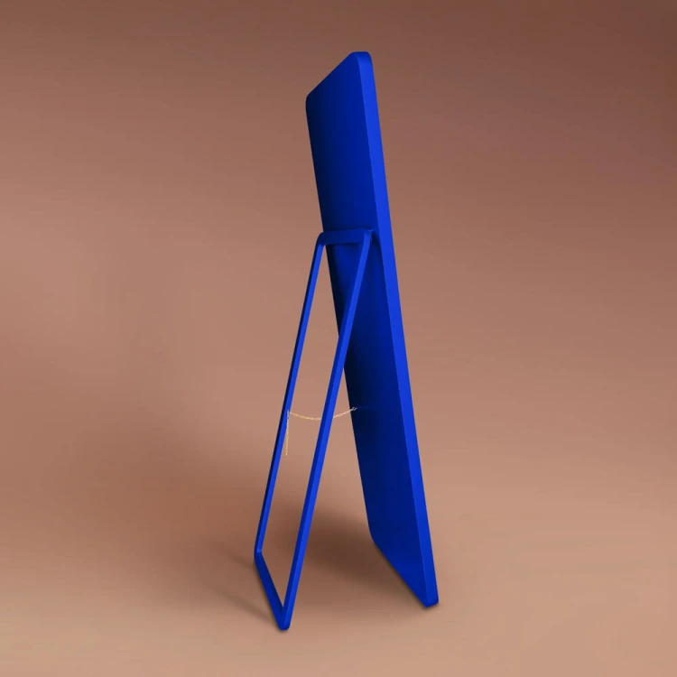Lustro stojące Billet w niebieskiej ramie, oparte na nodze zintegrowanej z plecami lustra.  Producent GieraDesign