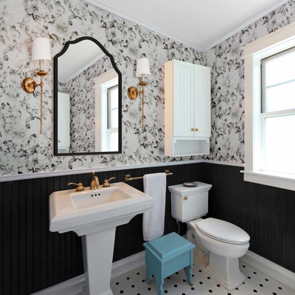 Czarne lustro w stylu vintage Grand Porto z ponadczasową ozdobną falą na tle kwiatowej tapety w stylowej łazience.
