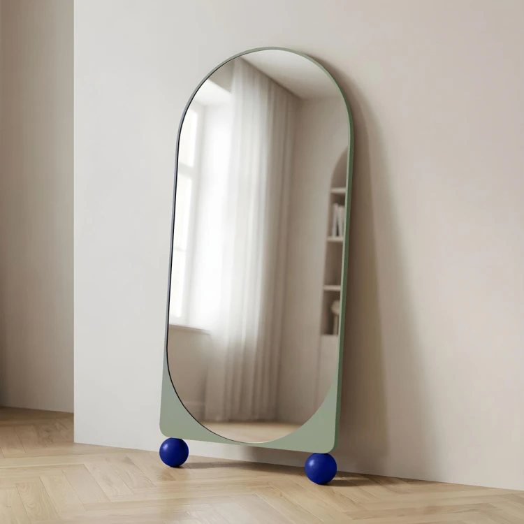 Lustro stojące na kulach noom, w kolorze miętowym, o parte o ścianę. GieraDesign