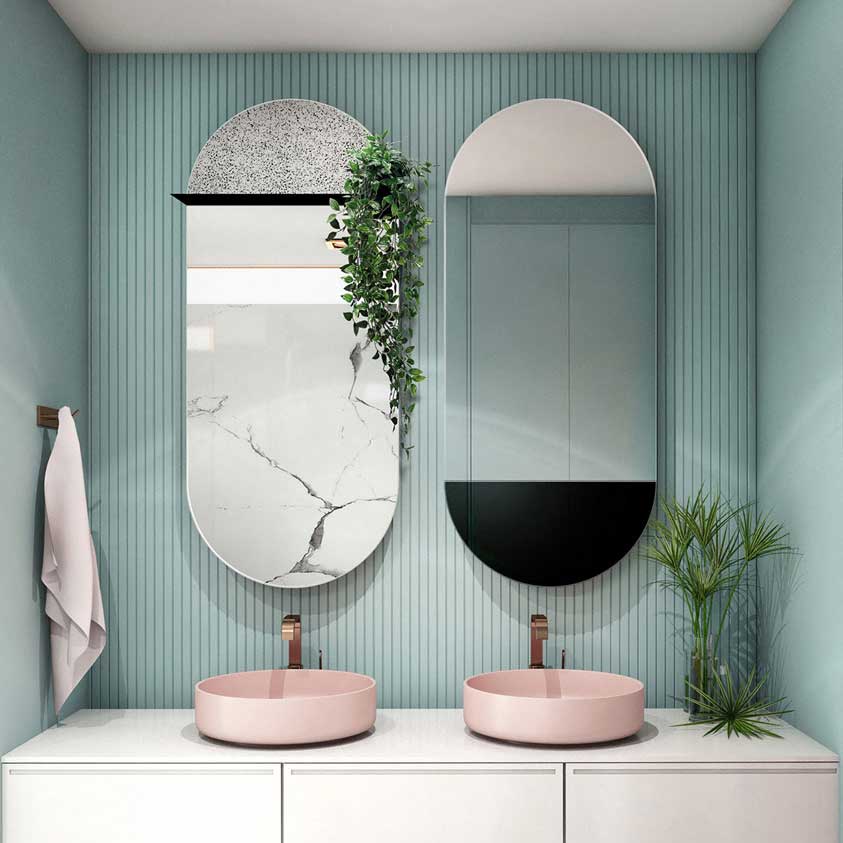 Dwa owalne lustra z kolekcji Fusion, wiszące obok siebie nad różowymi umywalkami w łazience. 