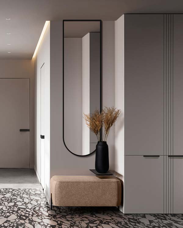 Wąskie lustro z łukiem  zawieszone nad siedziskiem w nowoczesnym przedpokoju