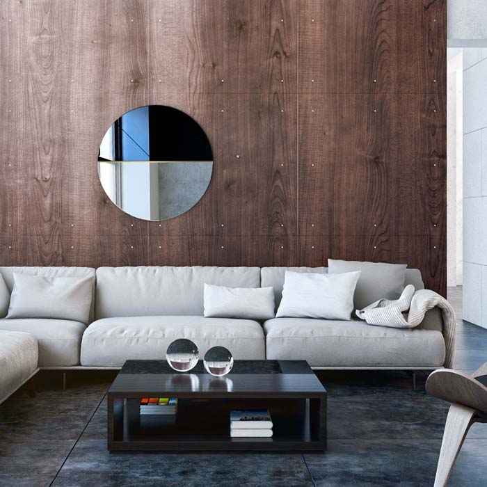 Dekoracyjne lustro Demi zawieszone na fornirowanej ścianie nad dużą kanapą wnowoczesnym salonie