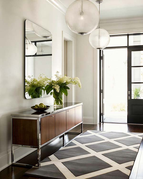 Lustro z zaokraglonymi rogami zawieszone symetrycznie nad komodą w korytarzu