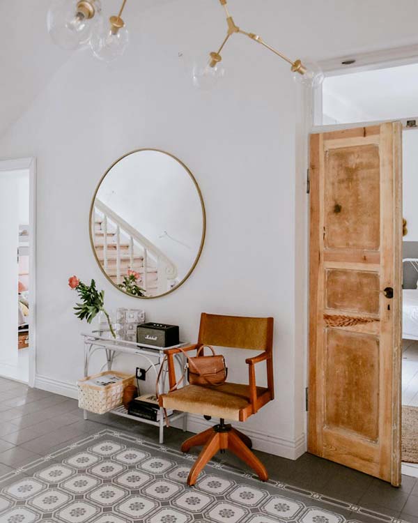 Okrągłe lustro w cienkiej złotej ramie w eklektycznym korytarzu 