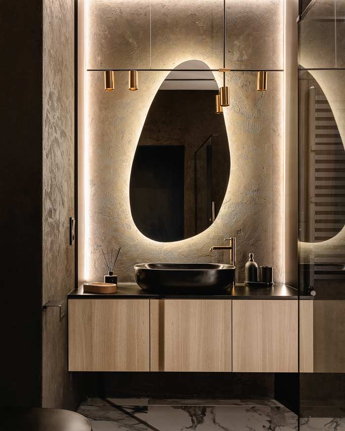 Organiczne lustro LED z podświetleniem w łazience w stylu modern luxury z czarną umywalką i złotymi akcentami
